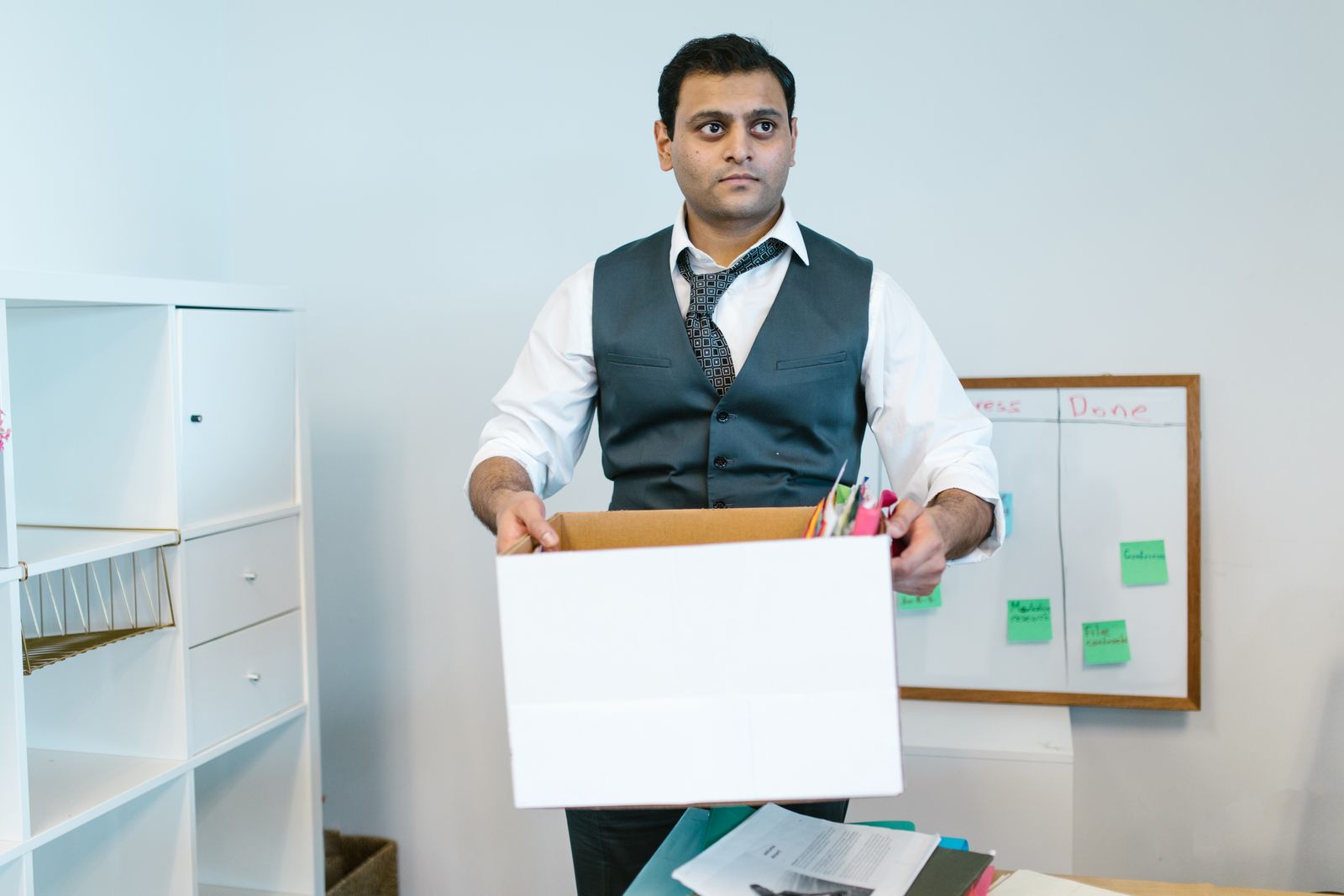 A departing employee packing personal belongings into a box at an office desk during offboarding.