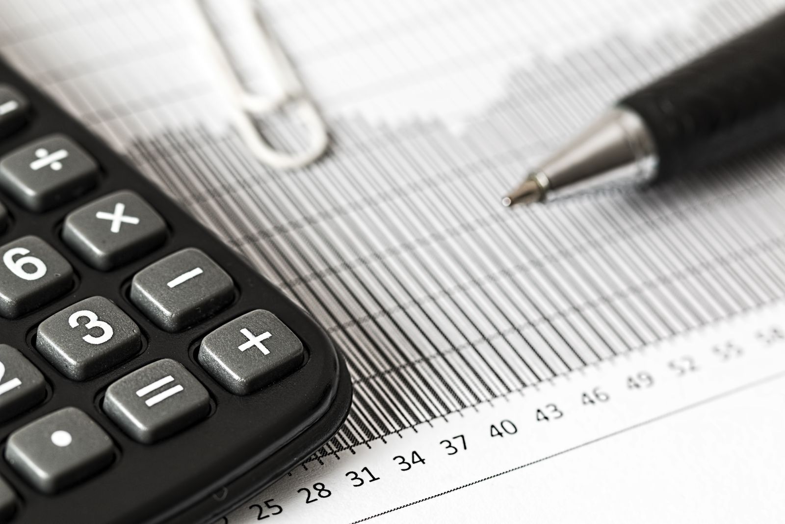 A calculator and pen resting on a printed bar graph, representing payroll cost analysis.