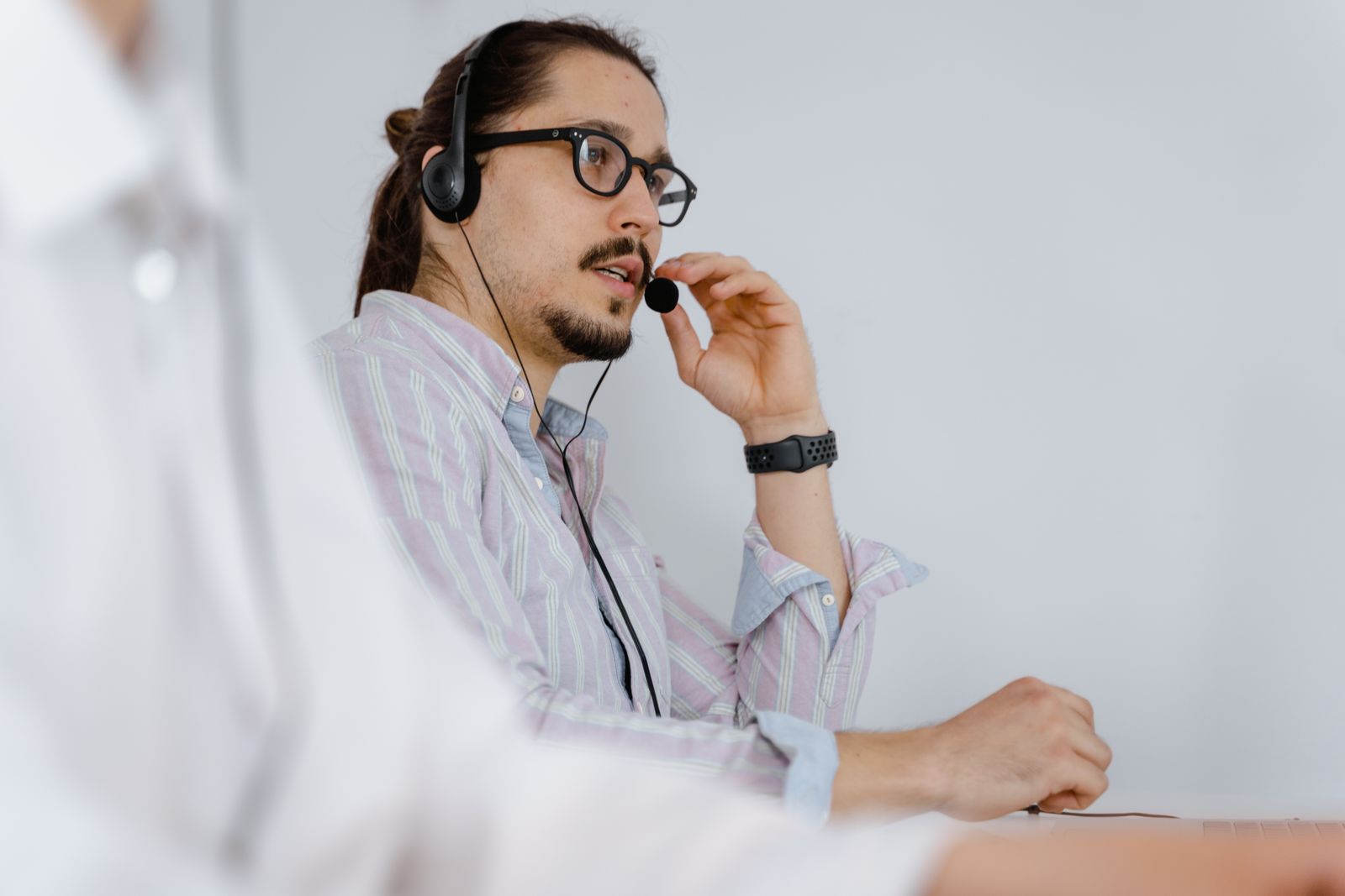 A customer support agent wearing a headset, focused on helping a caller in a modern office.