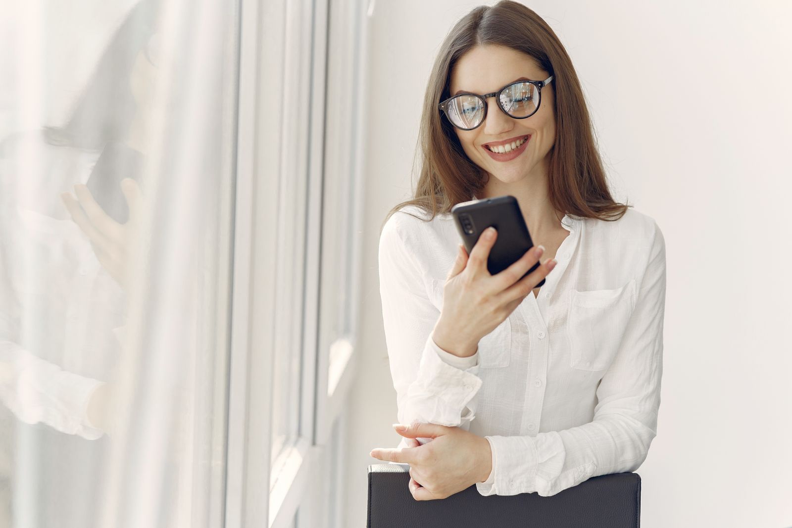 A woman messaging on her phone in a bright office, the kind of chat-style interaction the AI assistant is built for.