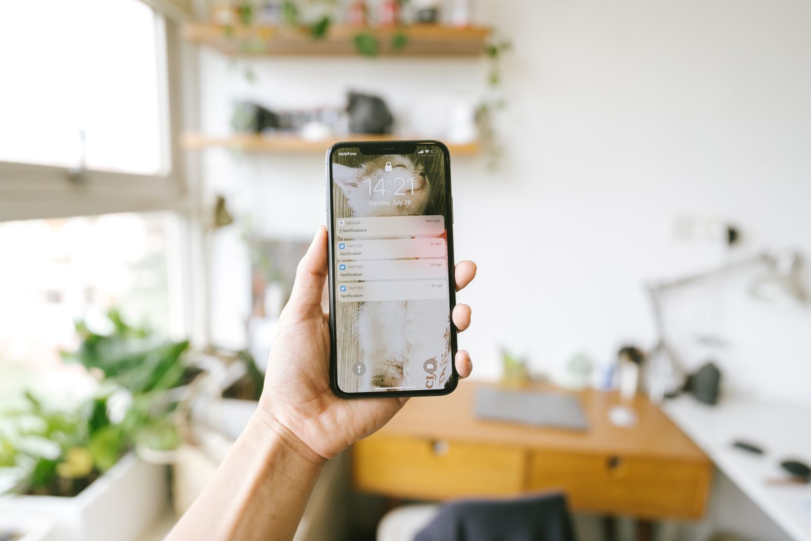 A person holding a smartphone in an office, focused on incoming notifications on the screen.