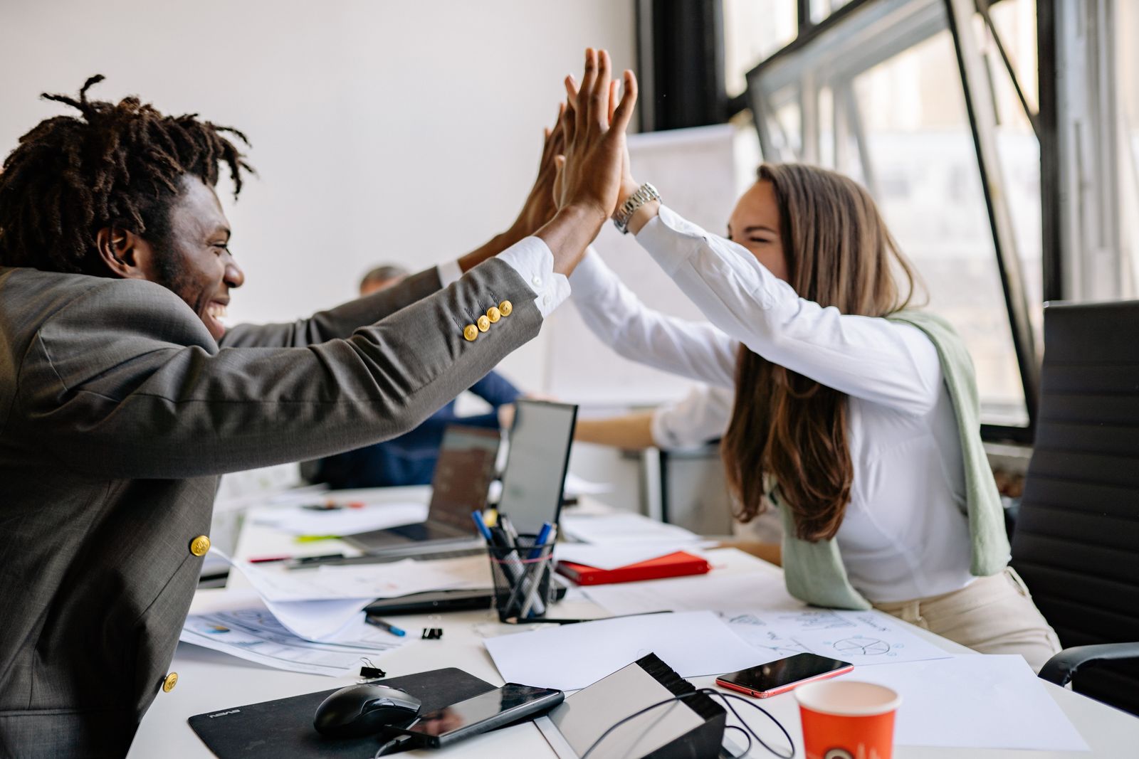 A group of colleagues celebrating together with a high-five in a modern office.