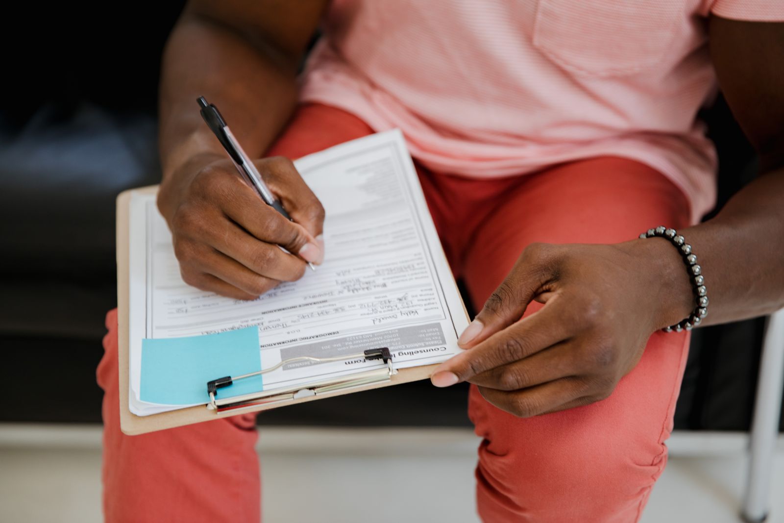 A hand filling out a feedback form attached to a clipboard.