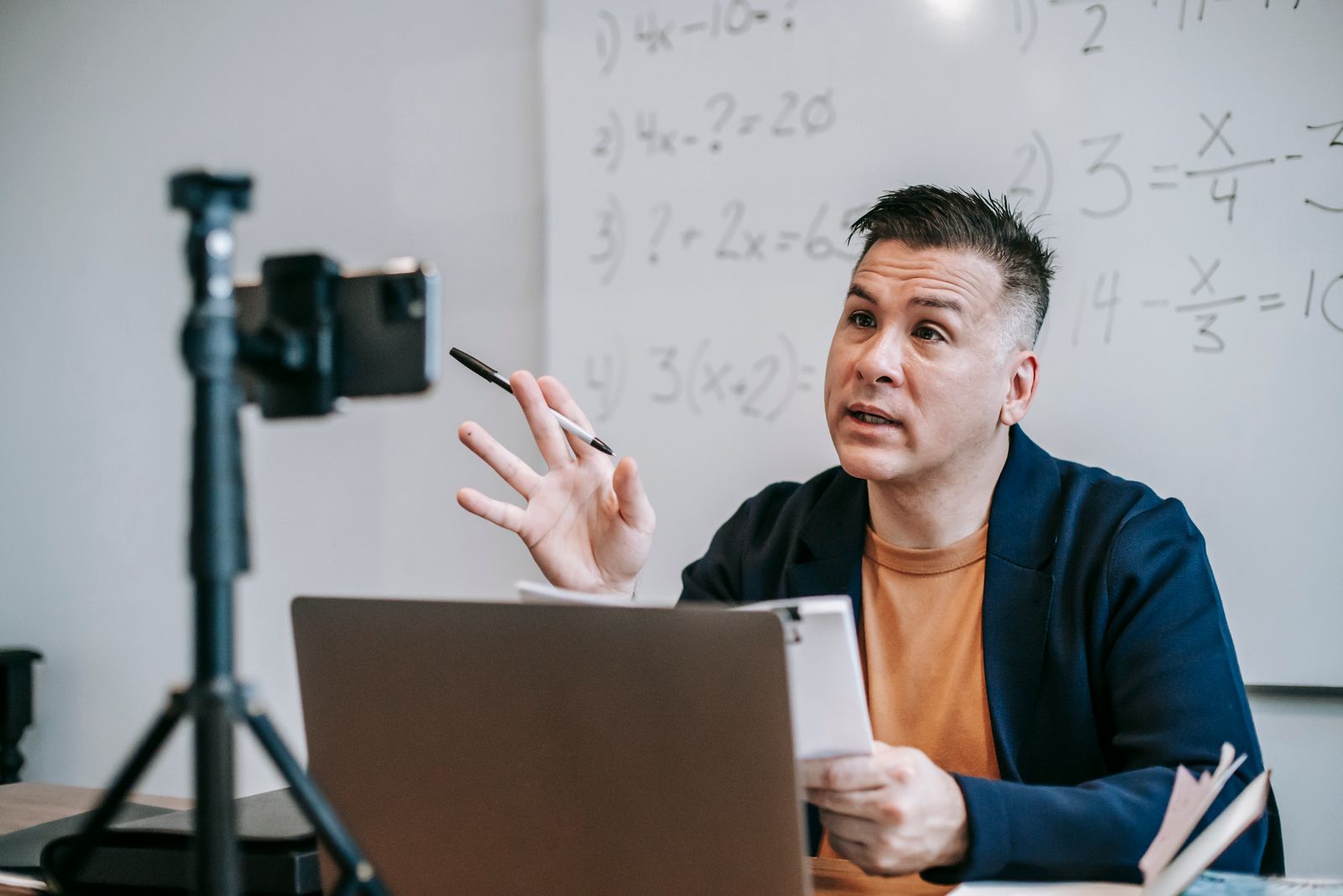 An instructor teaches a lesson online via laptop and webcam to remote students.