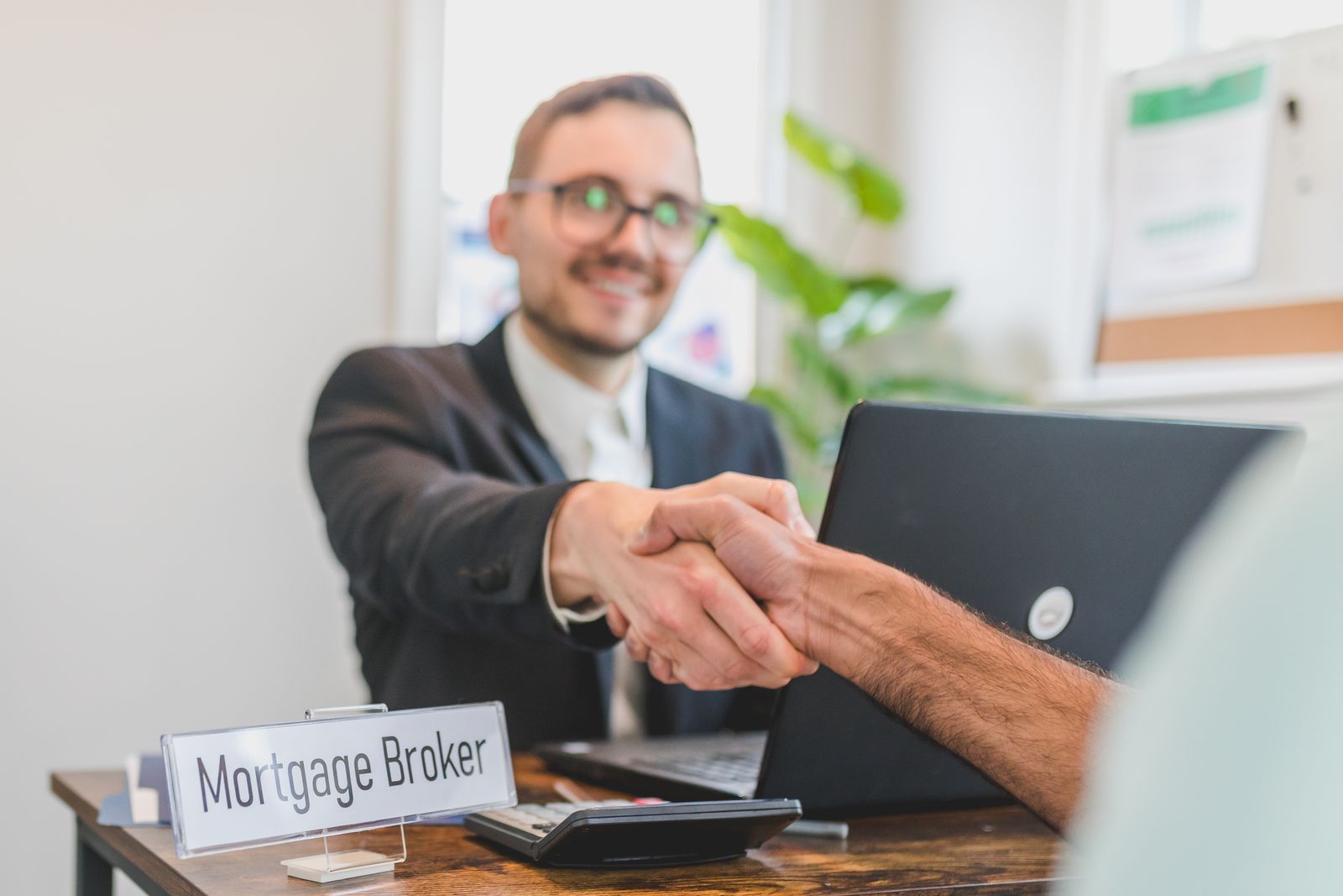 A mortgage broker and client sealing a loan agreement with a handshake