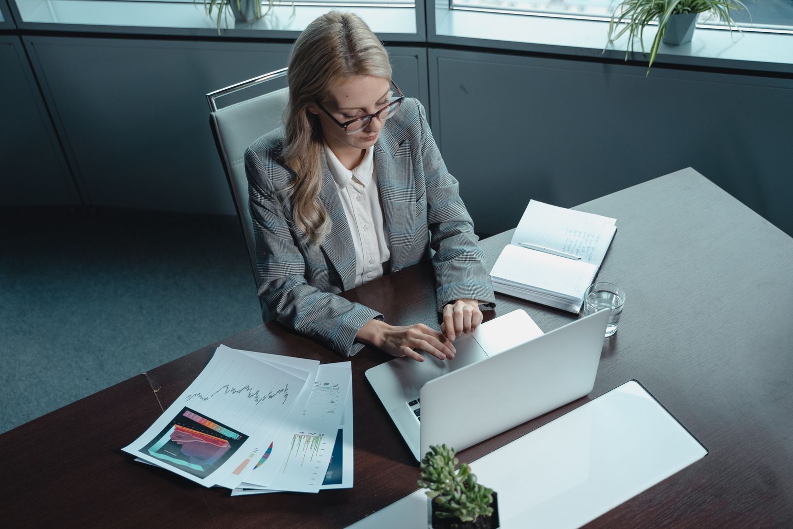 A professional working on a laptop with documents in a modern office