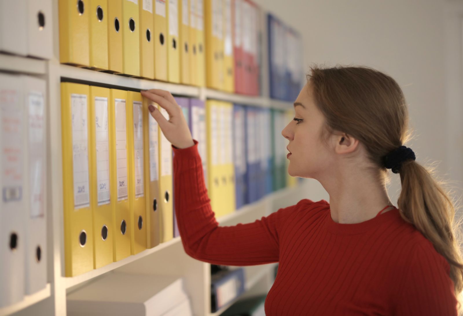 An office assistant selecting a document folder from a shelf