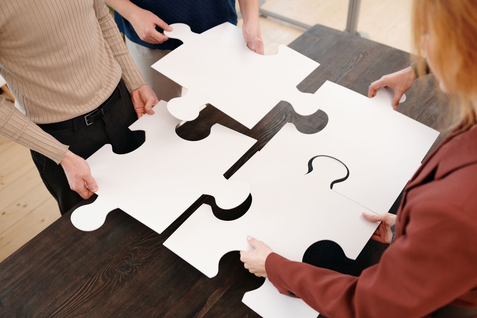 Four colleagues collaborating to assemble large puzzle pieces together