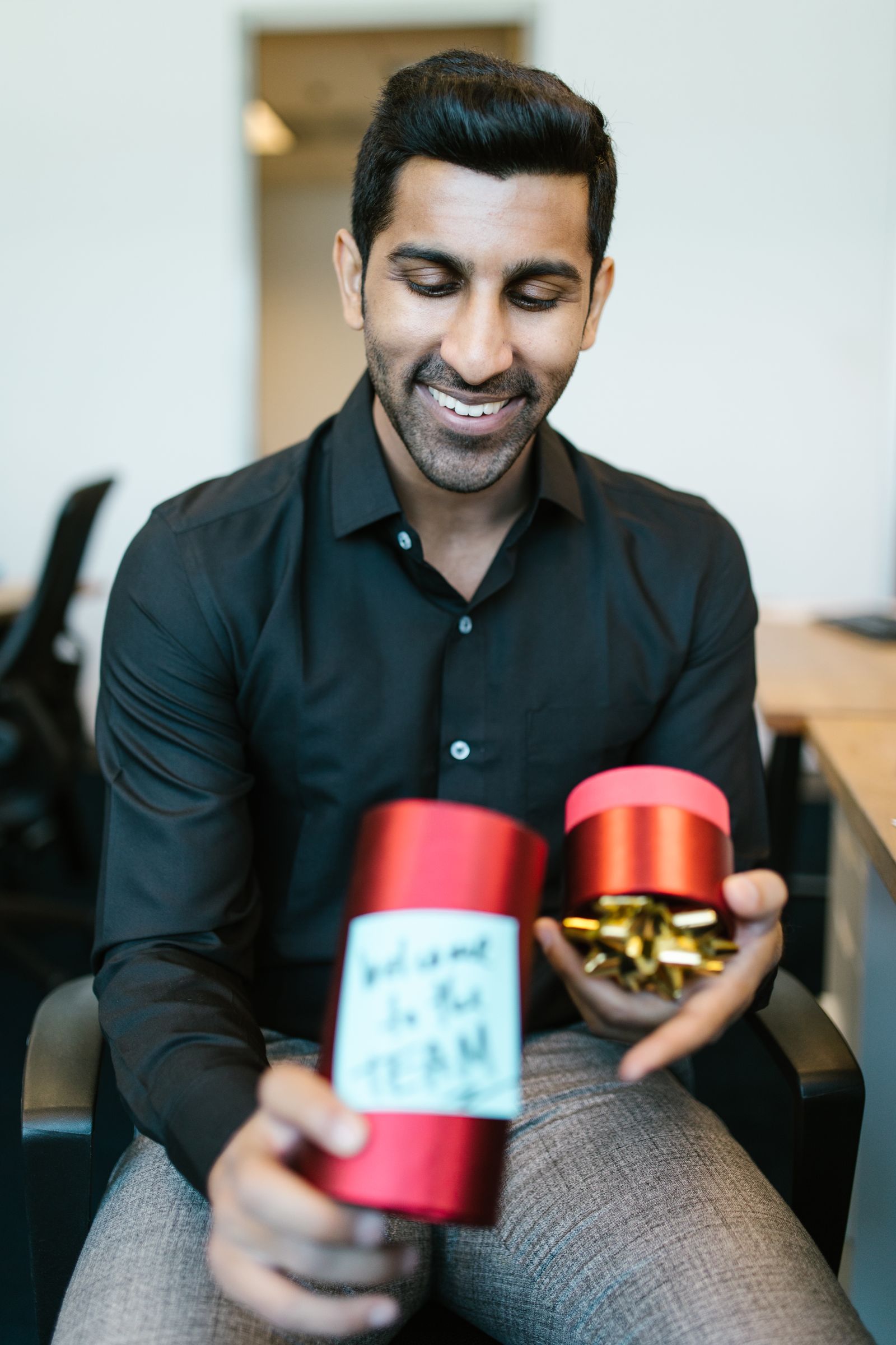 A smiling new hire holding a welcome gift box on their first day