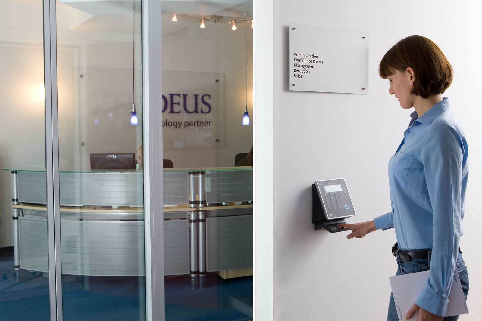 A woman using a biometric fingerprint scanner for secure access in a modern office.